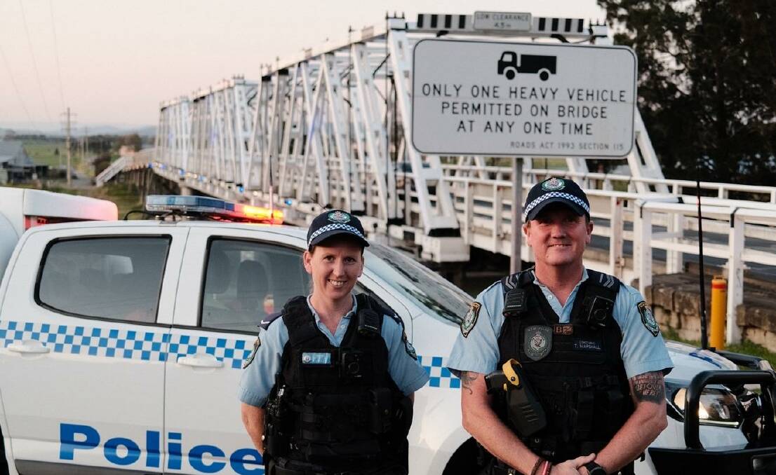 Port Stephens-Hunter Police District officers Michelle Chandler and Thomas Marshall in front of Morpeth bridge on Friday. Picture supplied