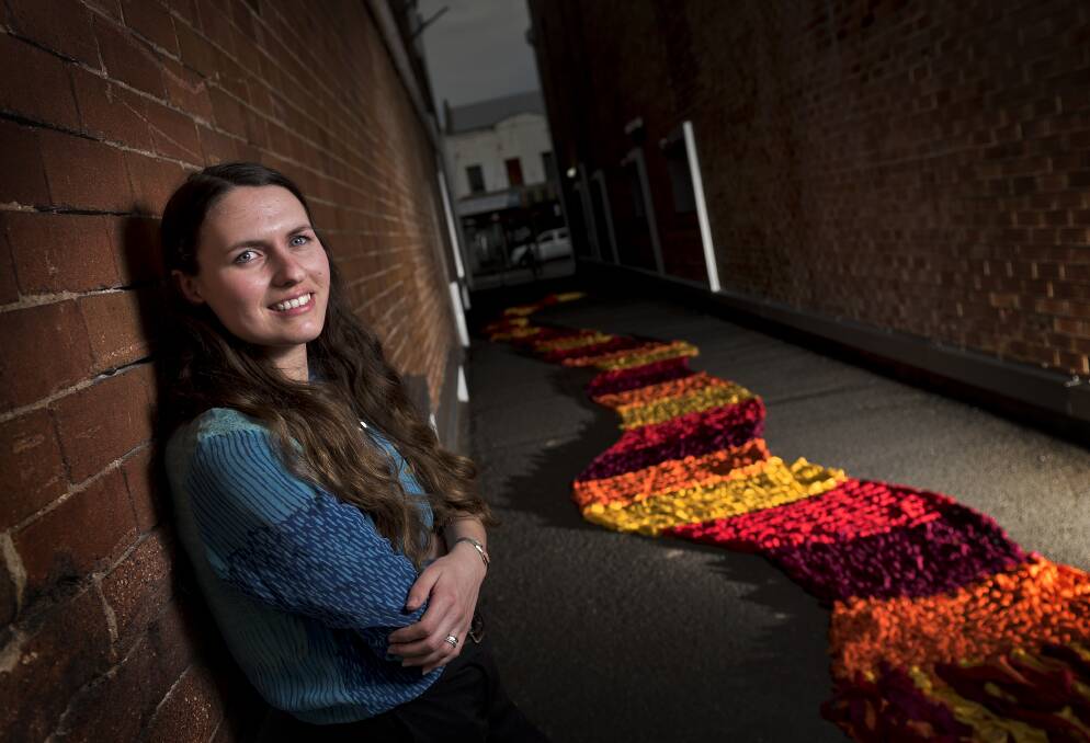 WARMING THE STREETS: Michaela Swan preparing to hang her knitted sculpture "Into the Wind" in the alley between the Levee and the riverside car park. Picture: PERRY DUFFIN